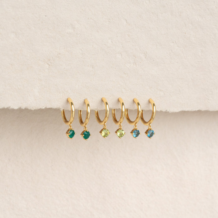 Six gold vermeil huggie earrings with green chalcedony and other colorful gemstones on a beige background, May Birthstone Drop Huggie Earrings - Green Chalcedony