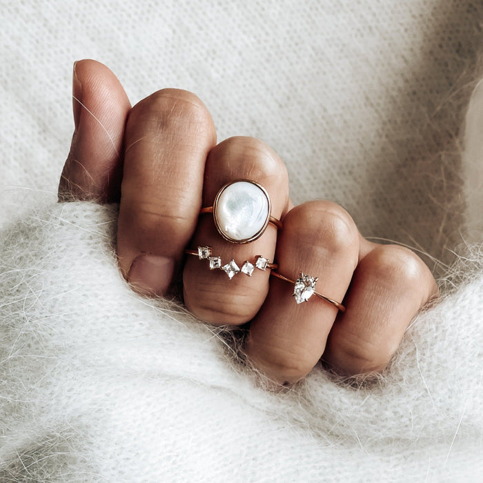 Silver mother of pearl ring stacked on hand with white topaz gemstone rings