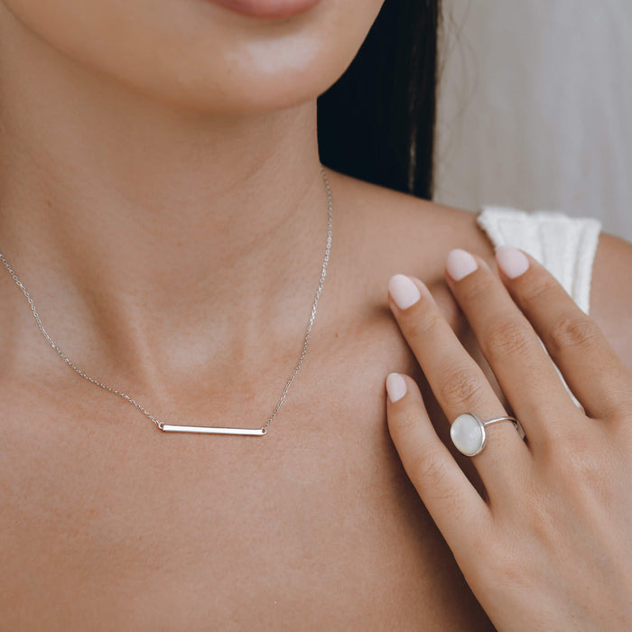 Silver round pearl ring on hand with silver bar necklace