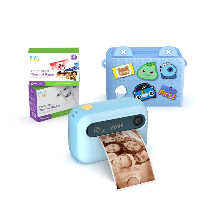 myFirst Insta 20 blue instant print camera for kids printing a photo, shown with a carrying bag, Color Burst thermal paper, and sticker rolls.