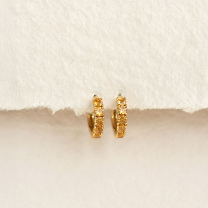 November Birthstone Huggie Earrings - Citrine with gold vermeil setting displayed on textured neutral background