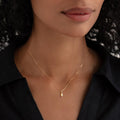 Close-up of woman wearing October Birthstone Pendant 14k Gold - Opal with a black collared shirt on a neutral background
