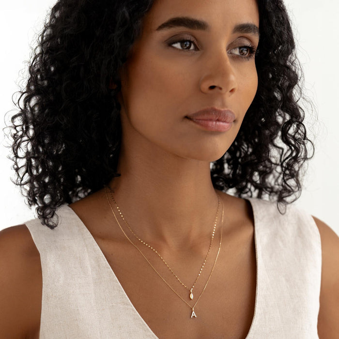 Close-up of woman wearing October Birthstone Pendant 14k Gold - Opal layered with a delicate gold letter A necklace