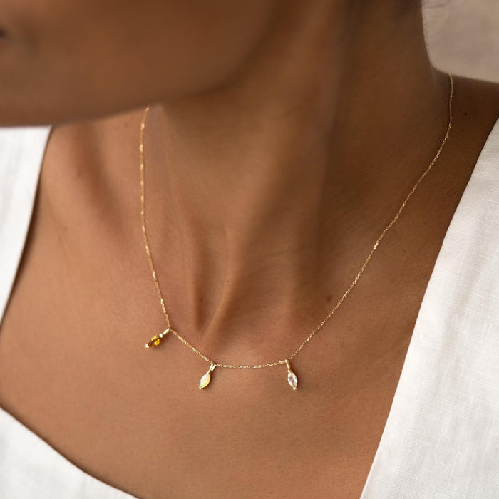 Close-up of a woman wearing the October Birthstone Pendant 14k Gold - Opal on a delicate gold chain with a white top