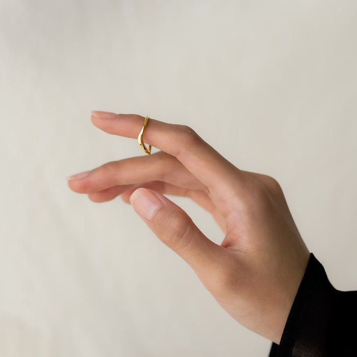 Close-up of a hand wearing the Organic Wavy Ring - Bea on the index finger against a neutral background