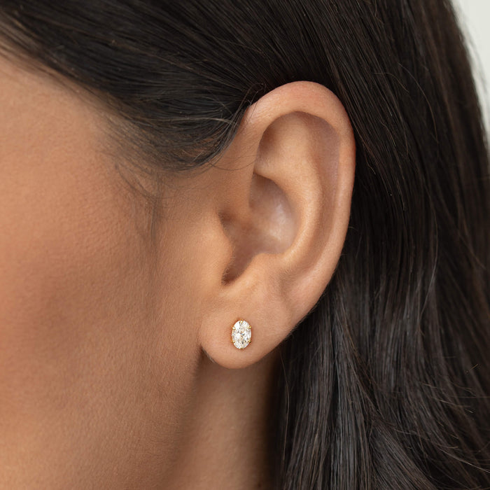 Close-up of a woman’s ear wearing a small oval-cut gemstone stud earring set in Gold Vermeil, shown on a natural skin tone with dark hair tucked behind the ear.
