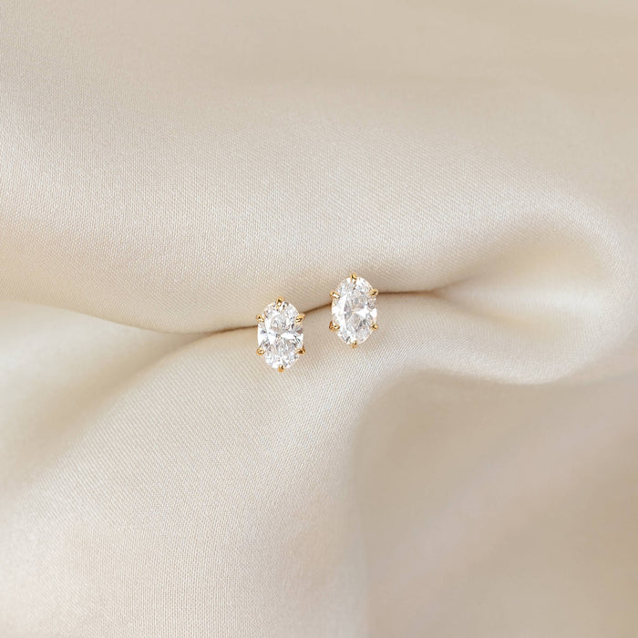 Pair of oval-cut gemstone stud earrings set in Gold Vermeil prongs, placed on softly draped ivory fabric for an elegant, minimal presentation.