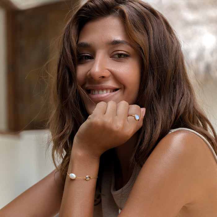 Irregular pearl on gold chain bracelet with sky blue topaz gemstone on woman