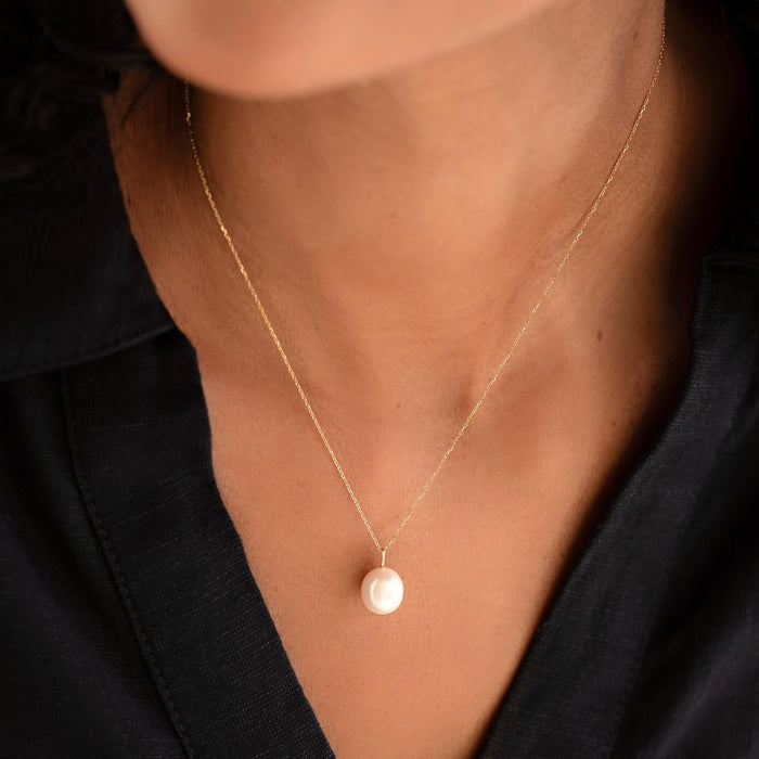Close-up of a woman wearing the Pearl Charm 14k Gold with a delicate 14k gold chain and black top