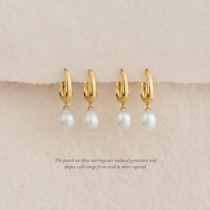 Close-up of four Pearl Drop Hoop Earrings - Maeve with gold vermeil and freshwater pearl drops on a beige background