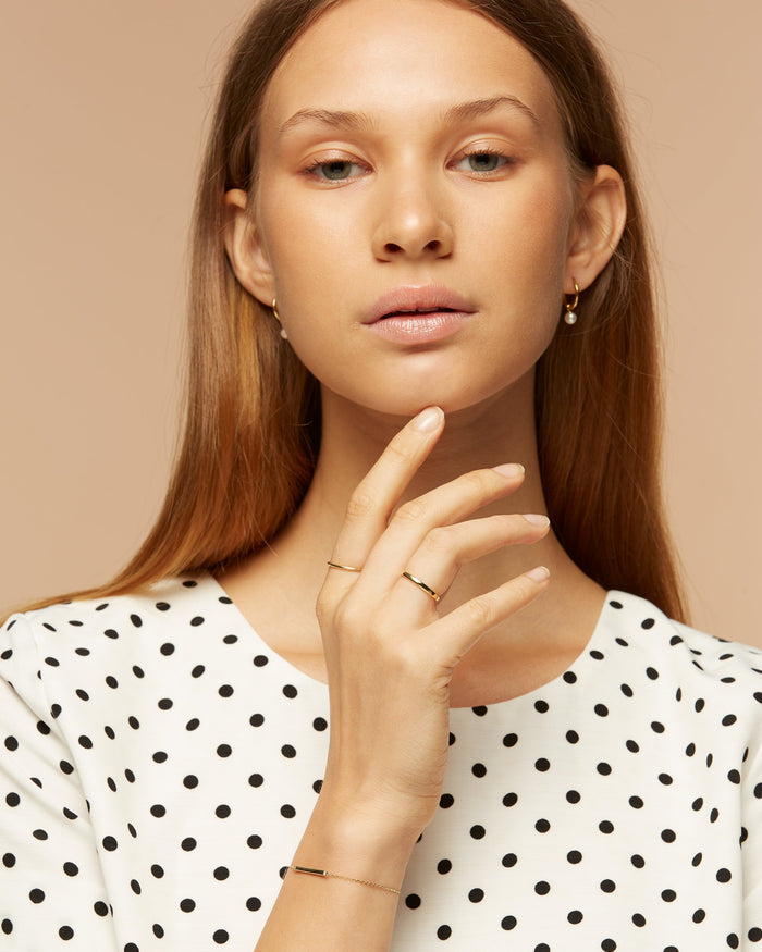 Silver pearl huggies on model with rings stack