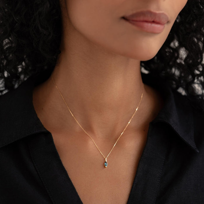 Close-up of woman wearing September Birthstone Pendant 14k Gold - London Blue Topaz with black top