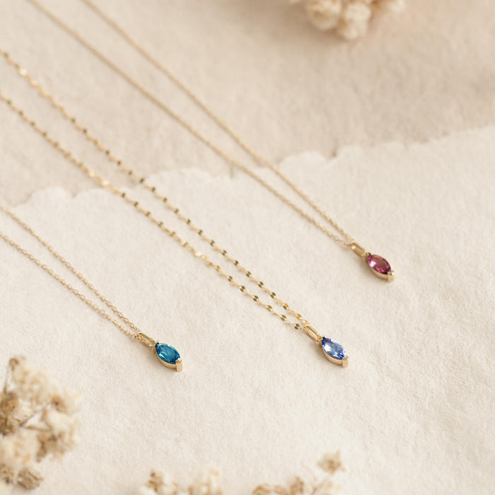 September Birthstone Pendant 14k Gold - London Blue Topaz marquise-cut pendant on delicate gold chain displayed on soft beige background