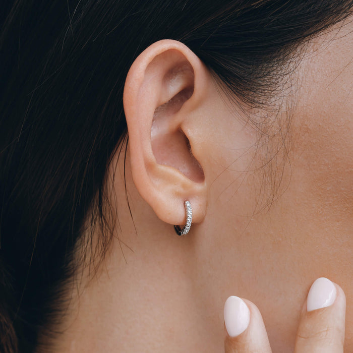 Huggie earrings in silver with white gemstones on model