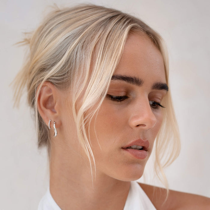 White topaz gemstone huggie earrings in silver on model