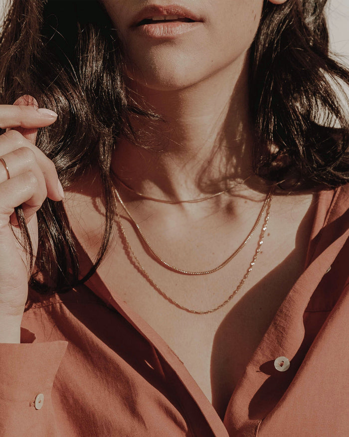 Gold thin chain necklaces layered on model