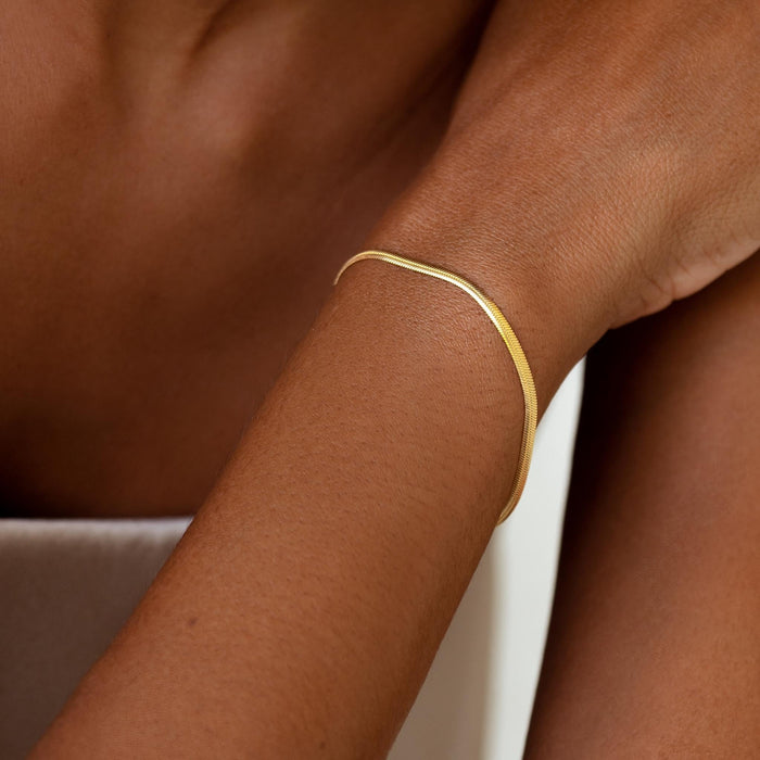 Close-up of a woman wearing a gold vermeil Snake Chain Bracelet with a smooth finish on bare skin