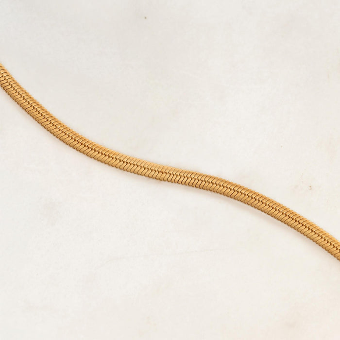 Close-up of the gold vermeil Snake Chain Bracelet with a smooth flexible texture on a light background