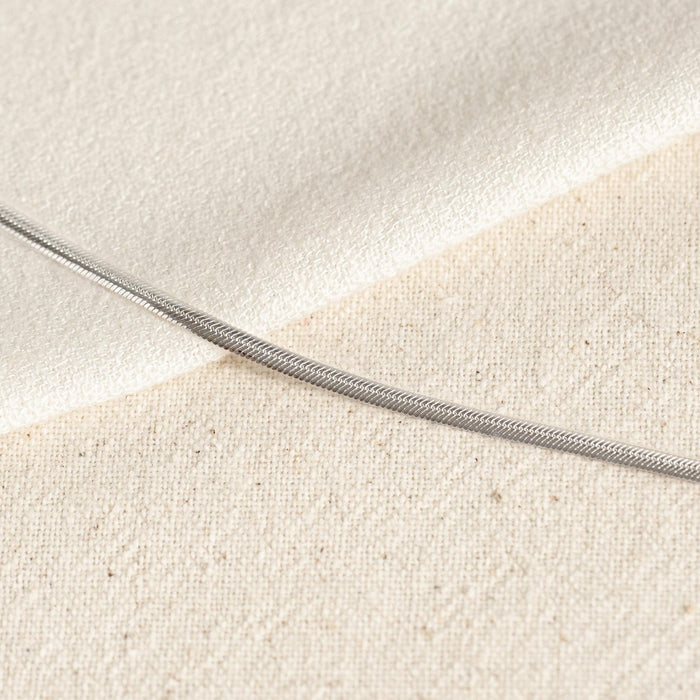 Snake Chain Necklace Silver displayed diagonally on a textured beige and white fabric background