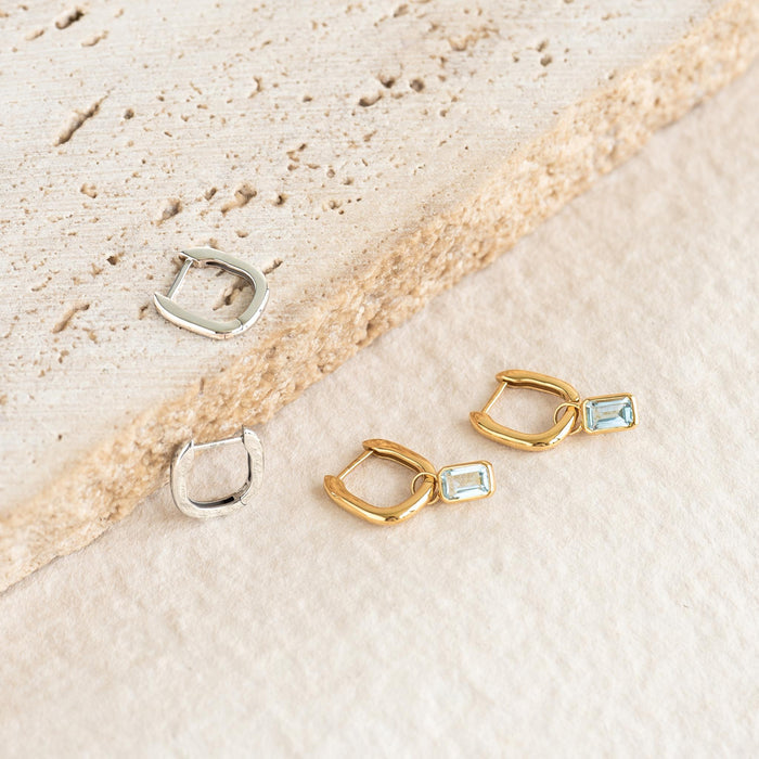 Square Huggie Earrings Silver - Amelia displayed with gold huggies featuring blue rectangular gemstones on textured surfaces