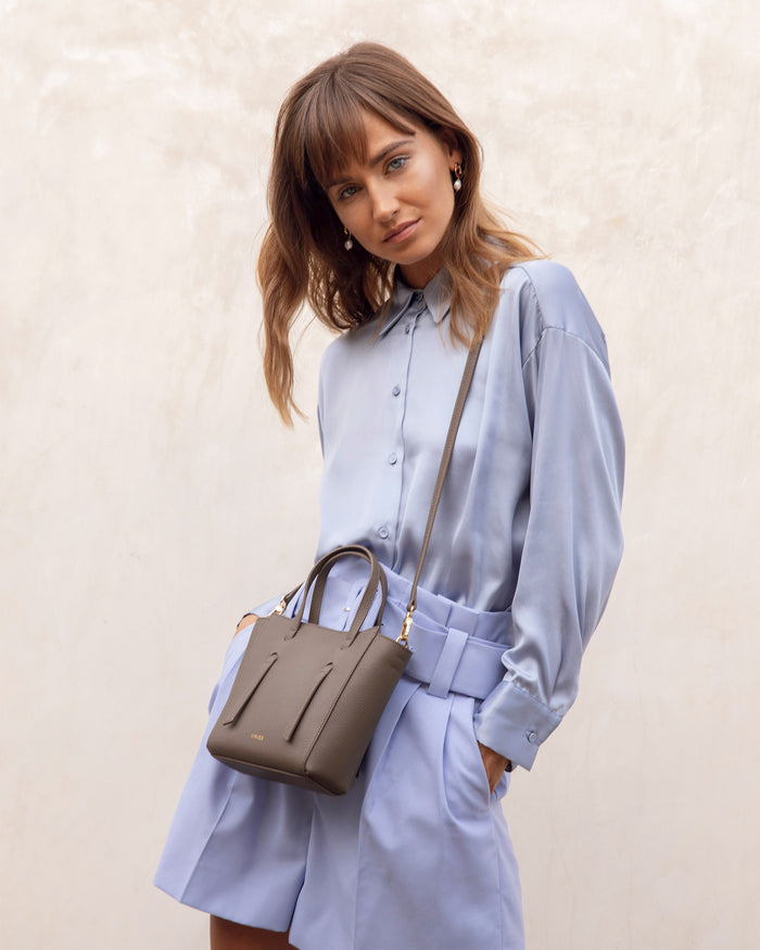 Woman wearing a light blue shirt and shorts styled with The Lana Bag - Blue crossbody mini purse
