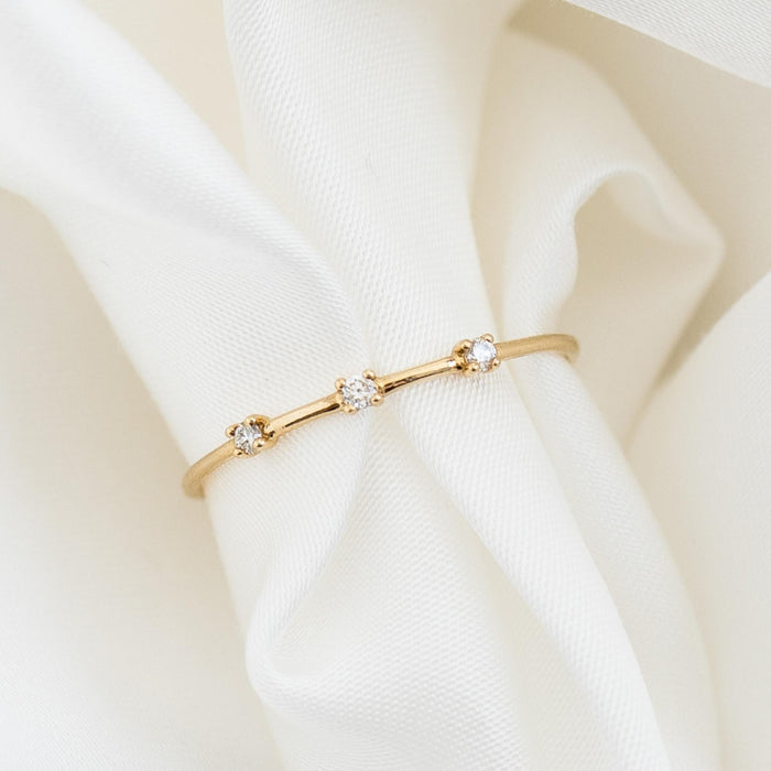 Three Stone Diamond Ring 14k Gold - Estelle with three delicate diamonds on a slim 14k gold band on white fabric background