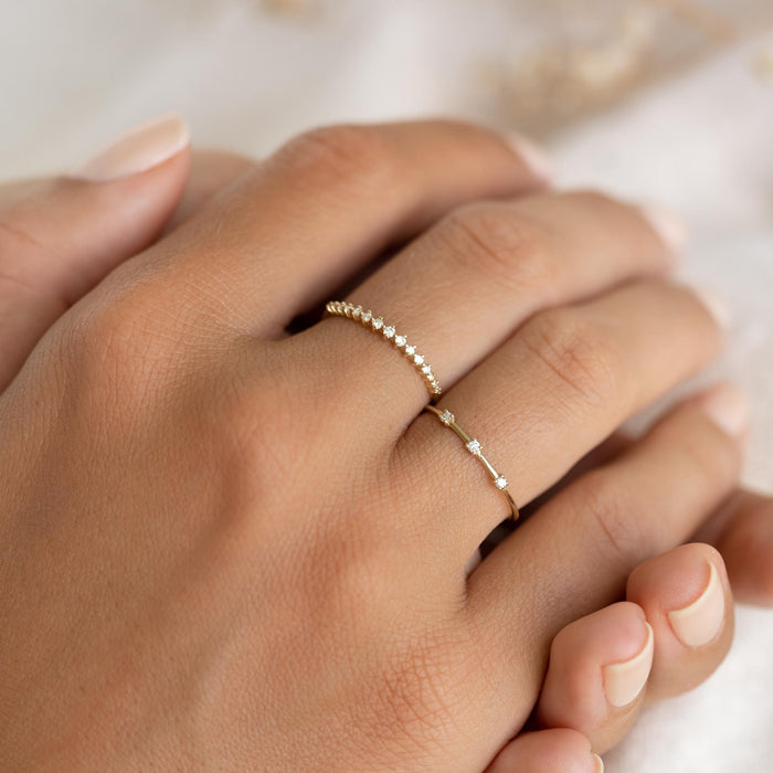 Close-up of a hand wearing the Three Stone Diamond Ring 14k Gold - Estelle on a neutral background