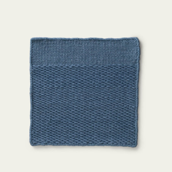 Blue textured rug on a light gray background, #seasideblue
